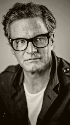 a man wearing glasses looking at the camera with a serious look on his face in black and white