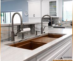 a kitchen with marble counter tops and stainless steel faucets, white cabinets and an island sink