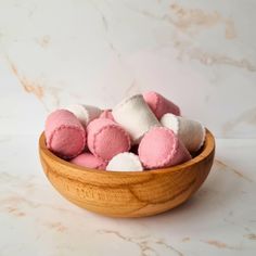 a wooden bowl filled with pink and white marshmallows