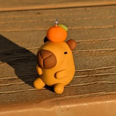 a small yellow toy sitting on top of a wooden table next to a wall and floor