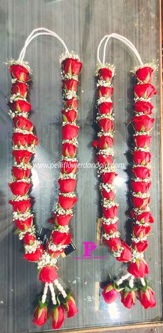 two red flowers are attached to the side of a glass wall with white string and beads