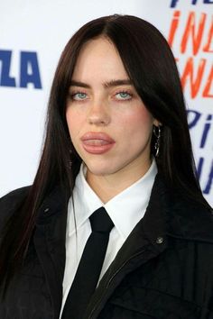 a close up of a person wearing a suit and tie with her tongue sticking out