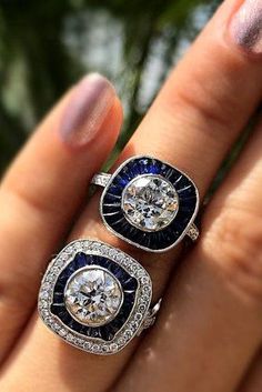 two diamond and sapphire rings on someone's finger, one with a blue ring