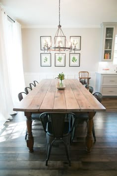 a dining room table with chairs and pictures on the wall