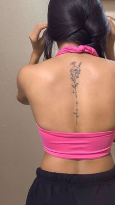 the back of a woman's neck with flowers tattooed on her upper and lower back