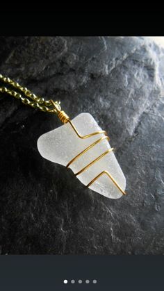 a piece of glass sitting on top of a gold plated metal chain with an arrow charm attached to it