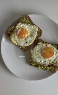 two pieces of toast with an egg on top and avocado in the middle