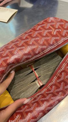 a woman's hand is opening the inside of a red and white patterned purse