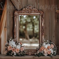 an ornate gold framed mirror sitting on top of a wooden shelf next to flowers and greenery