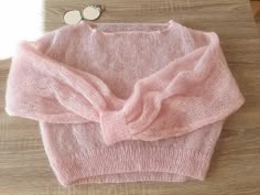 a pink sweater sitting on top of a wooden table