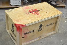 a wooden box sitting on top of a floor next to a table with tools in it