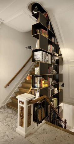 a staircase with bookshelves and stairs leading up to the second floor in a home