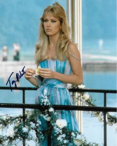 an autographed photo of a woman in a blue dress on a balcony overlooking the ocean