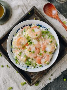 a bowl filled with rice and shrimp on top of a table next to a wooden spoon