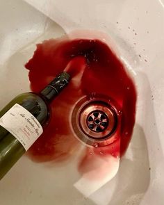 a bottle of wine sitting in a sink next to a faucet with blood on it