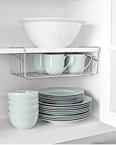 dishes and cups are stacked on the shelf