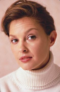 an old photo of a woman wearing a turtle neck sweater and looking at the camera