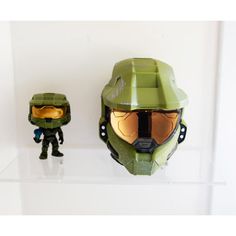 two action figures are on display in a glass case, one is wearing a green helmet and the other has an orange visor