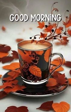 a cup of coffee sitting on top of a saucer next to leaves and the words good morning