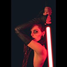 a woman holding a light saber up to her head with both hands and one arm