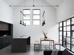 an open kitchen and dining area with black furniture in the center, along with large windows