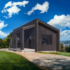 a small wooden building sitting on top of a lush green field under a blue sky