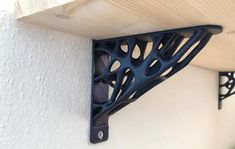 a wooden shelf with metal brackets on it and a white wall in the back ground