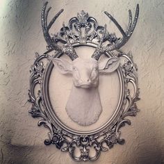 a deer's head is mounted to the wall in a frame with ornate designs