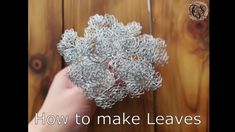 a person is holding some silver wire on top of a wooden table with the words how to make leaves