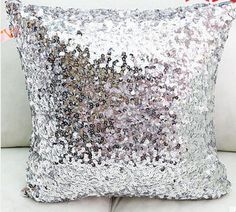 a silver sequin pillow sitting on top of a white table