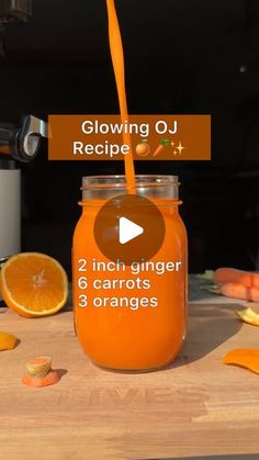 a glass jar filled with orange juice sitting on top of a wooden table next to sliced oranges