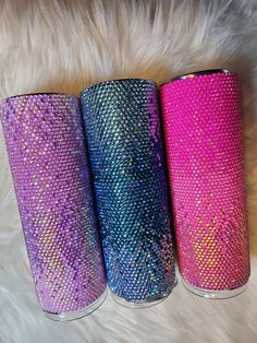 three different colored tumbles sitting next to each other on a white fur covered floor