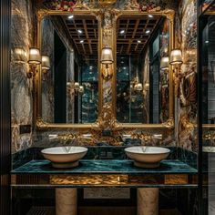 a fancy bathroom with two sinks and large mirrors on the wall above them is decorated in gold, black and white marble