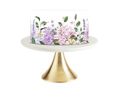 a white cake with pink and purple flowers on it sitting on top of a gold pedestal