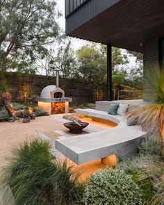 Create a layered, organic look in your fire pit area by mixing grasses and trees of varying heights and textures, complementing the structured elements seamlessly. This coastal garden, featuring a cozy fire pit with a curved concrete seat, pizza oven, and built-in lighting, is the perfect year-round outdoor space. Click to see more of this stunning design.@cos.design