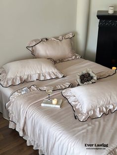 two white beds with ruffles and pillows on top of each other in a room