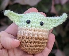 a small crocheted yoda toy is in someone's hand