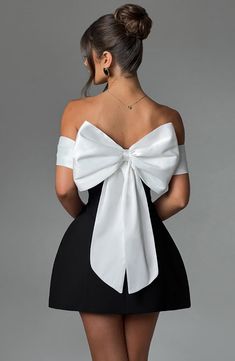 a woman in a short black and white dress with a big bow on the back