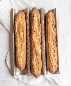 three long loafs of bread sitting on top of a metal tray next to each other