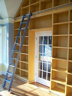 a ladder leaning up against a wall next to a door and book shelf with books on it