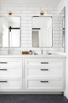 a white bathroom with two sinks and mirrors