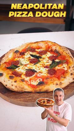 a man holding a pizza on top of a wooden cutting board next to a cardboard cutout