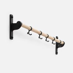 a black and white coat rack with three hooks on the back of it, hanging from a wall