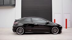 a black car parked in front of a garage door