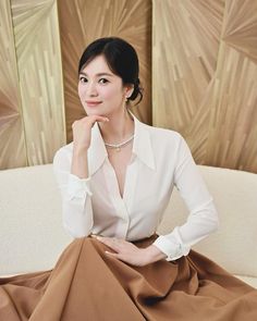 a woman sitting on top of a white couch next to a brown skirt and shirt