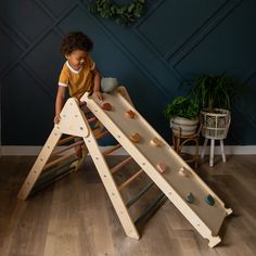 a little boy playing with a wooden climbing frame