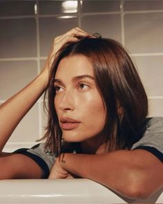 a woman sitting in a bathtub with her hands on her head and looking off to the side