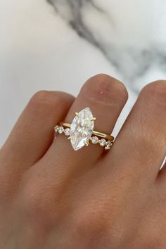 a woman's hand with a diamond ring on top of her finger and a marble background