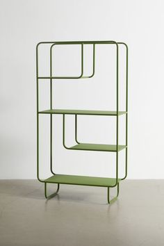 a green shelf sitting on top of a floor next to a white wall with shelves