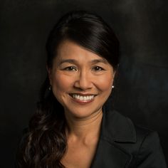 a woman in a black jacket smiling at the camera